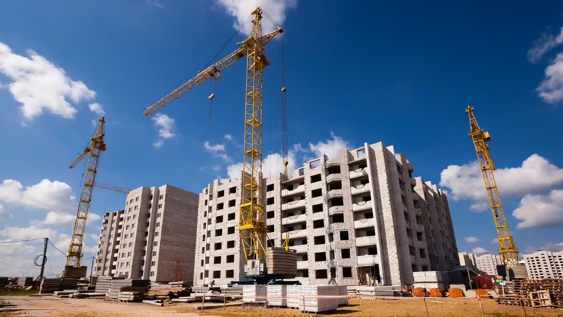 Construção civil com vários guindastes e edifício em crescimento sob céu azul