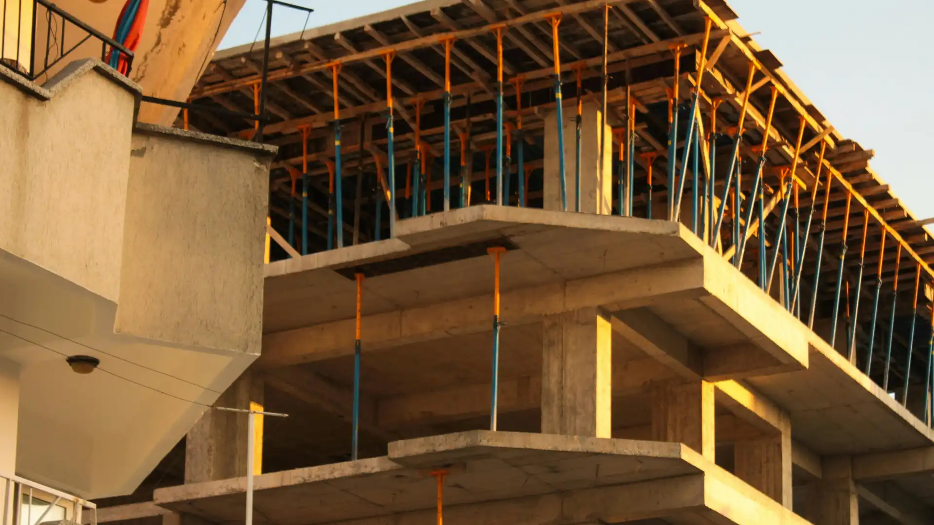 Construção de edifício em andamento com estruturas de concreto e apoio de andaimes, reforçando o processo de construção civil.